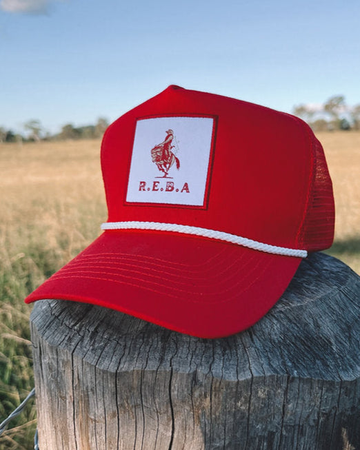 Red cap with a logo on a wooden post against a blue sky and field background