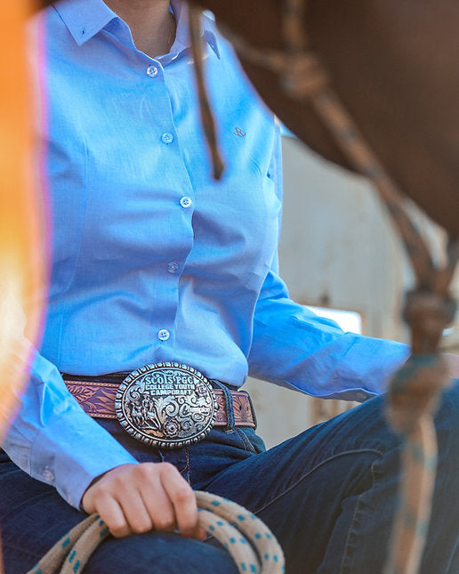 Person wearing a blue shirt and jeans with a decorative belt, holding a rope.