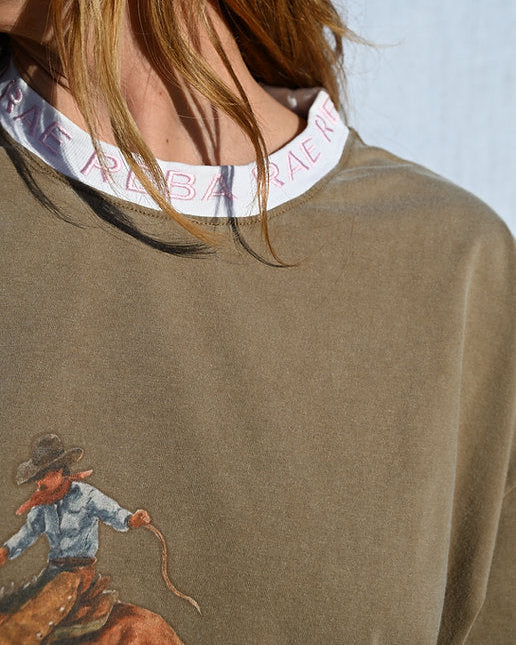 Close-up of a person wearing a brown sweatshirt with a cowboy graphic and Ralph Lauren collar.