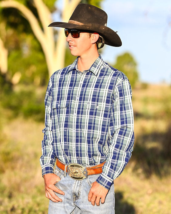 Man wearing a plaid shirt, cowboy hat, and sunglasses outdoors.