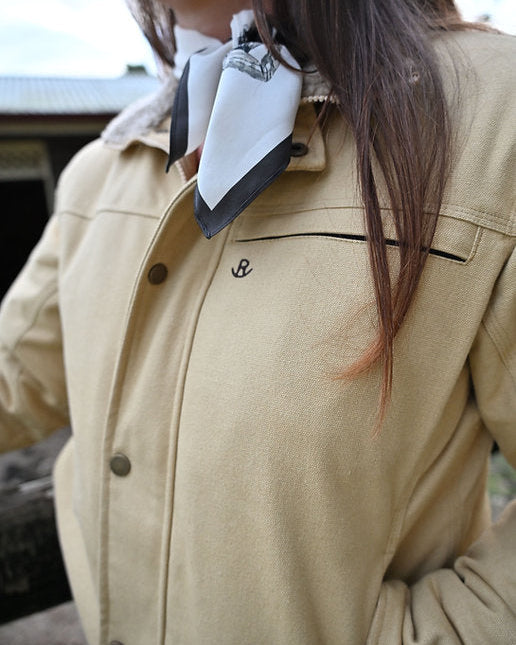 Person wearing a beige jacket with a white and black scarf around their neck.