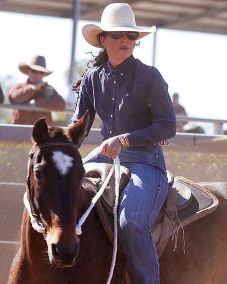 Person riding a horse in a rodeo arena with another person in the background.