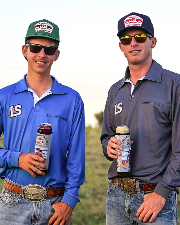 Two men in outdoor attire holding bottles, standing in a field.