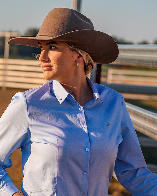 Woman wearing a brown cowboy hat and blue shirt outdoors