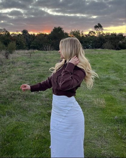 Woman standing in a field with a sunset in the background